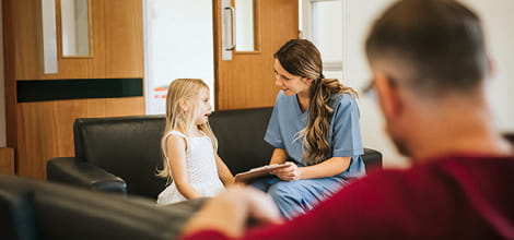Dental nurse speaking to young patient with father in the foreground